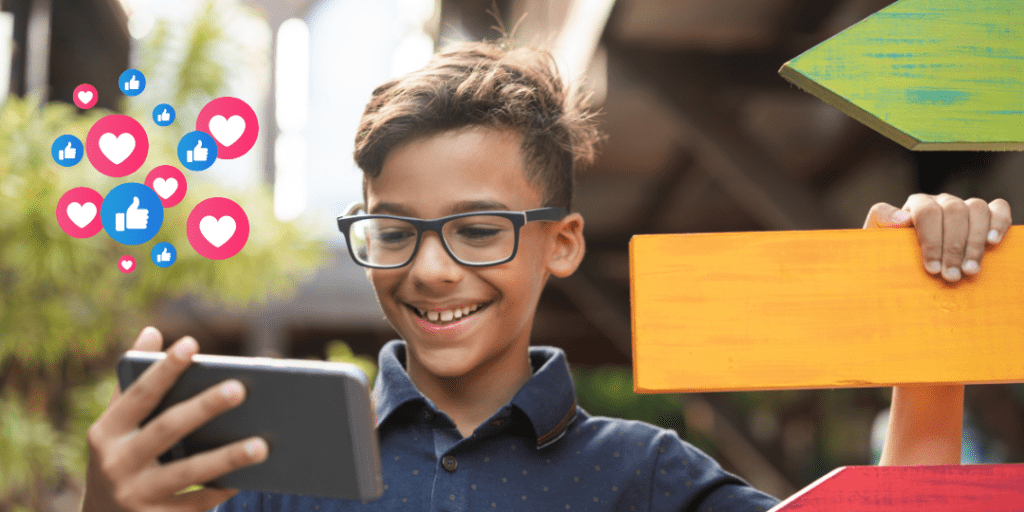 child near blank signs looking at phone with like and love icons 