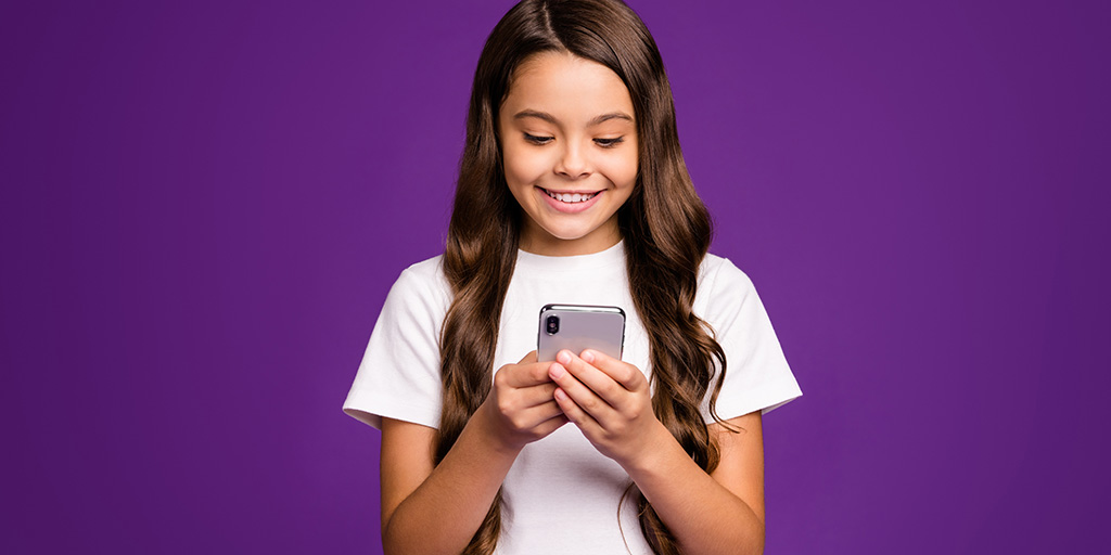 Tween girl looking excitedly at an iPhone she's holding