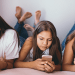 Group of girls scrolling phones on bed