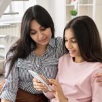 Mother and daughter looking at phone on couch