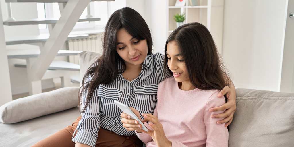 Mother and daughter looking at phone on couch