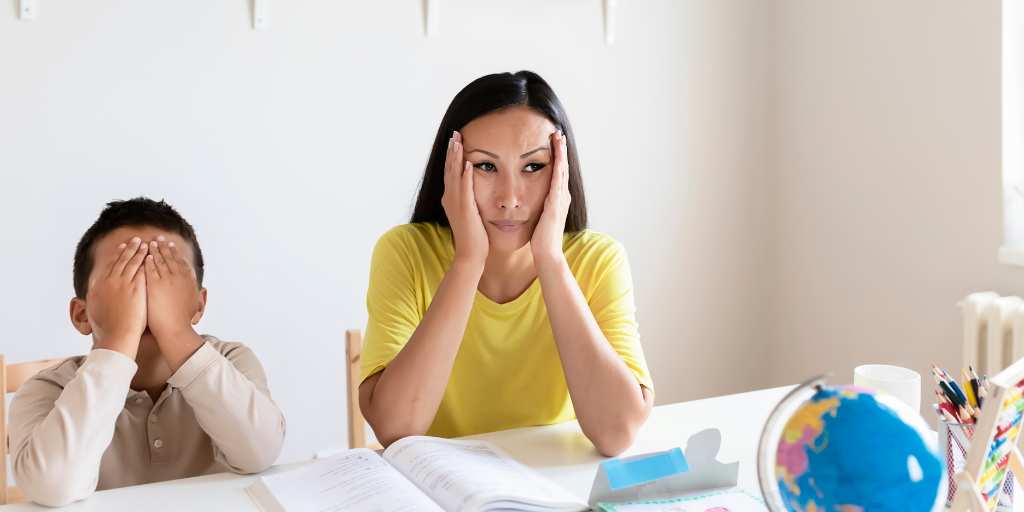 Frustrated mother with hands on face next to son