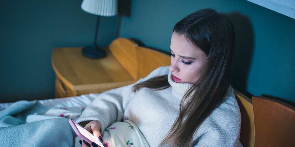 Sad teen on phone in bed