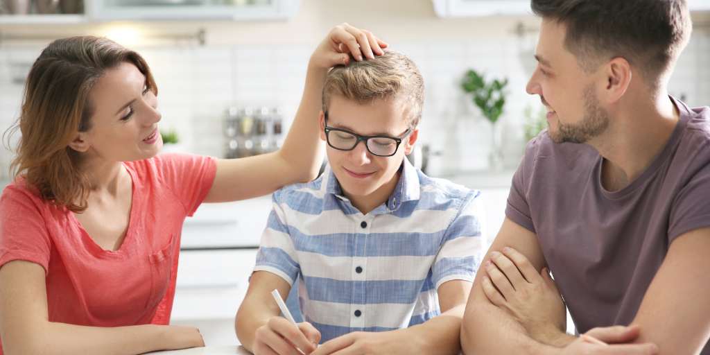 parents with son at table while mother ruffles child's hair