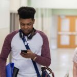 Teen looking at phone in school hallway