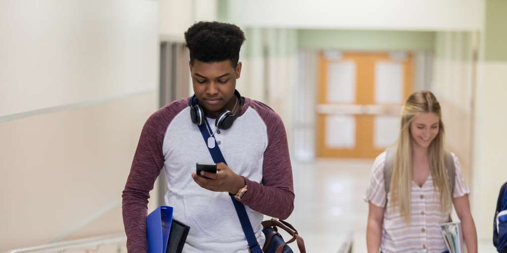 Teen looking at phone in school hallway