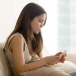 Teen girl looking at phone on couch