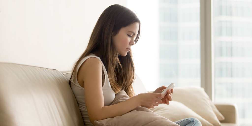 Teen girl looking at phone on couch