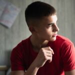 Teen boy in bedroom looking toward window