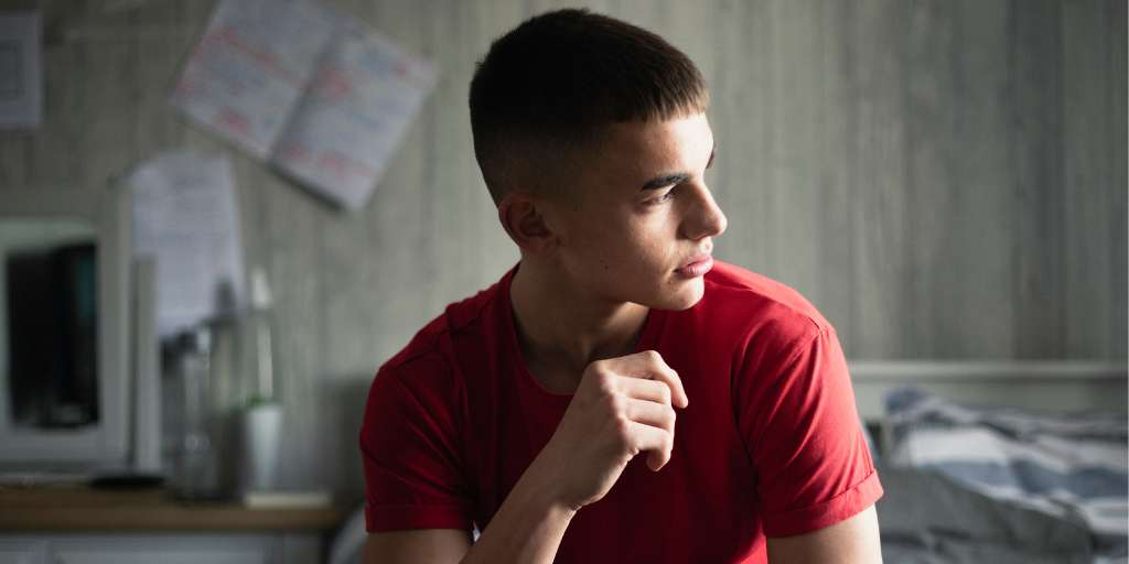 Teen boy in bedroom looking toward window