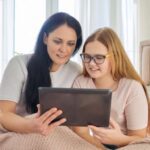 Mother and daughter on bed looking at tablet