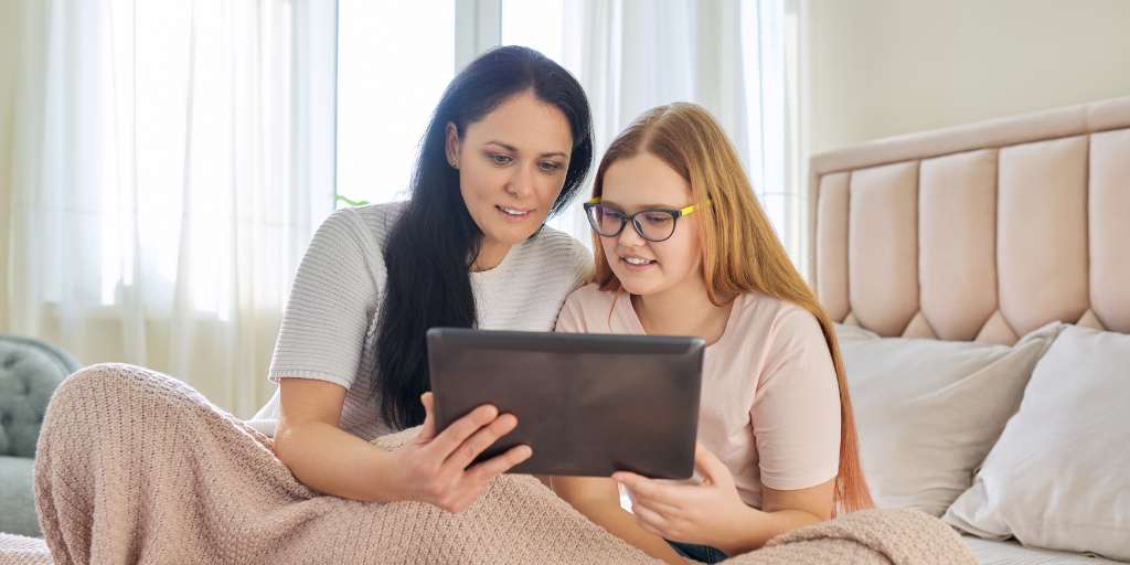 Mother and daughter on bed looking at tablet
