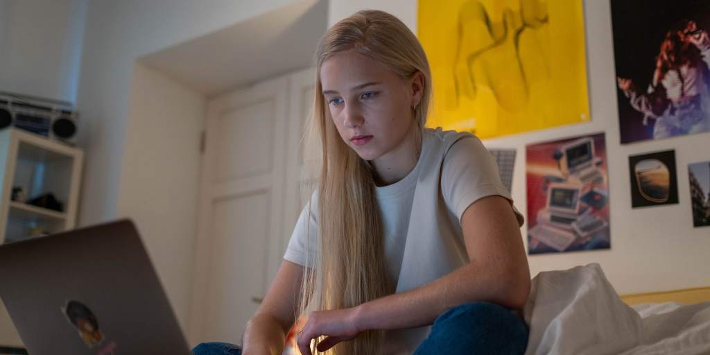 teen girl using laptop in bedroom