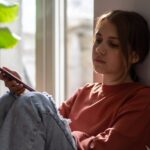 Young girl looking morose while leaning against wall