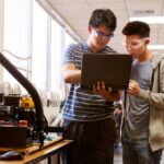 teen boys looking at laptop while building device
