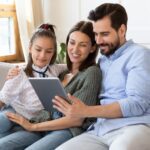 Family looking at tablet with Google parental controls together on couch
