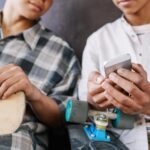 Two teen boys looking at manosphere content on phone