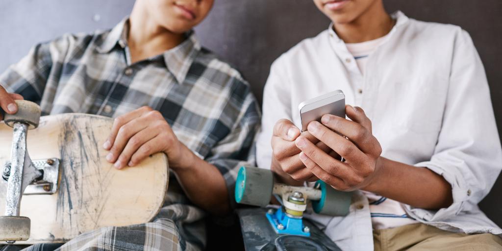 Two teen boys looking at manosphere content on phone