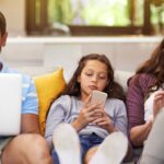 family looking at devices on couch