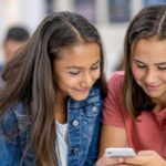 two girls looking at phone in class
