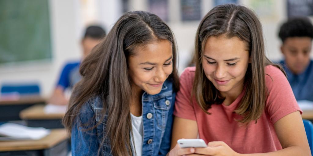 two girls looking at phone in class