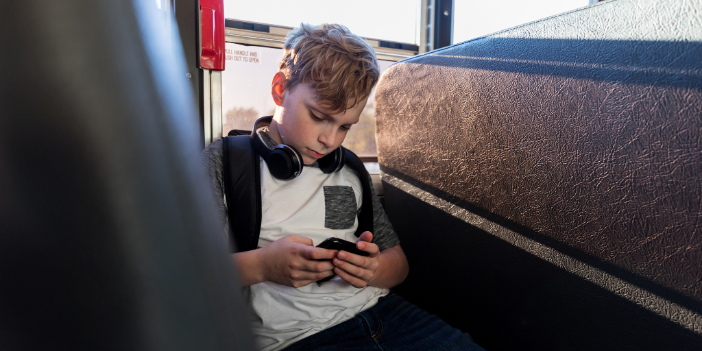 Young boy using phone on bus