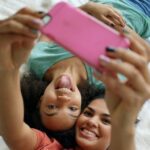 Two friends using iPhone to take selfie