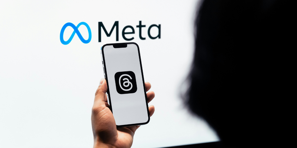 Person looking at phone with Meta logo in background