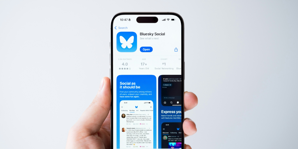Hand holding phone with Bluesky app on it